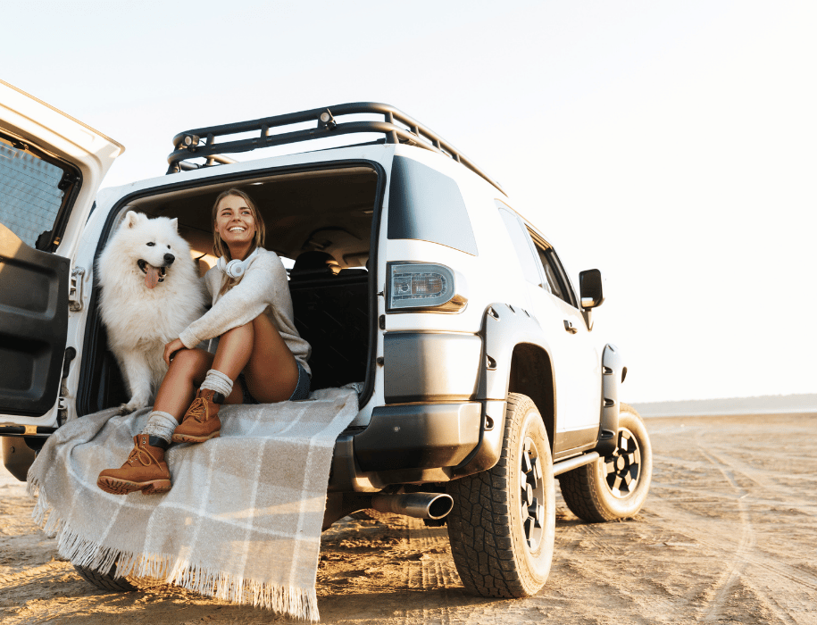 Woman and dog sitting in back of SUV
