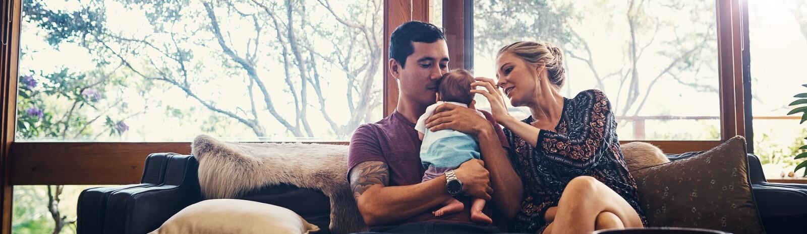 young couple with an infant together on a couch
