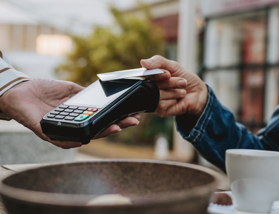 close-up of a hand holding a credit card up to a payment processor 