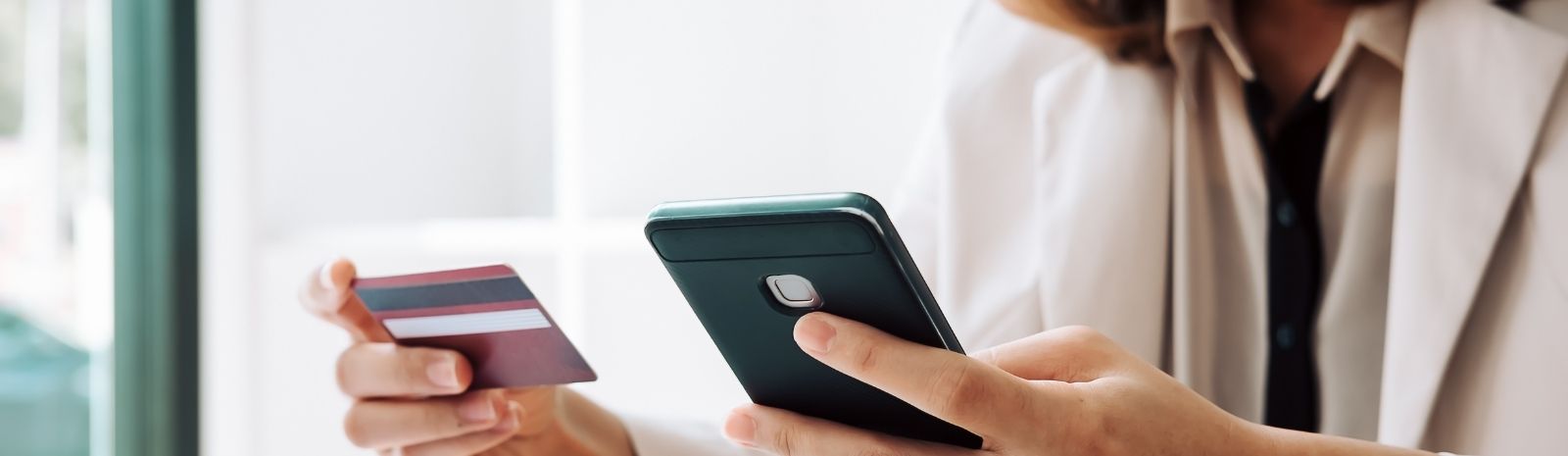 Person holding cell phone and business credit card