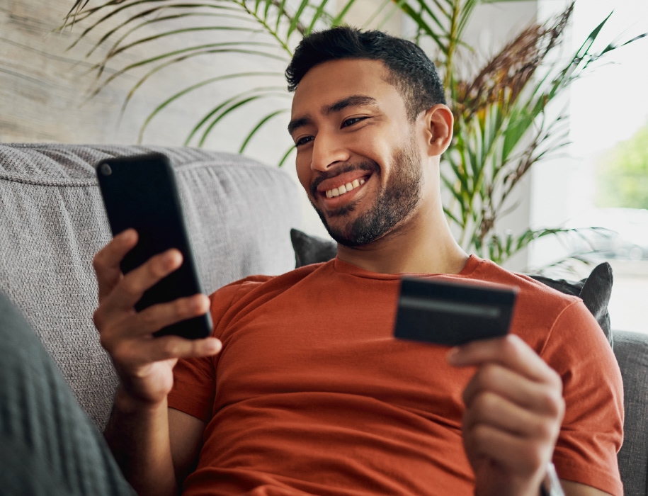 young man holding a credit card and looking at a smartphone