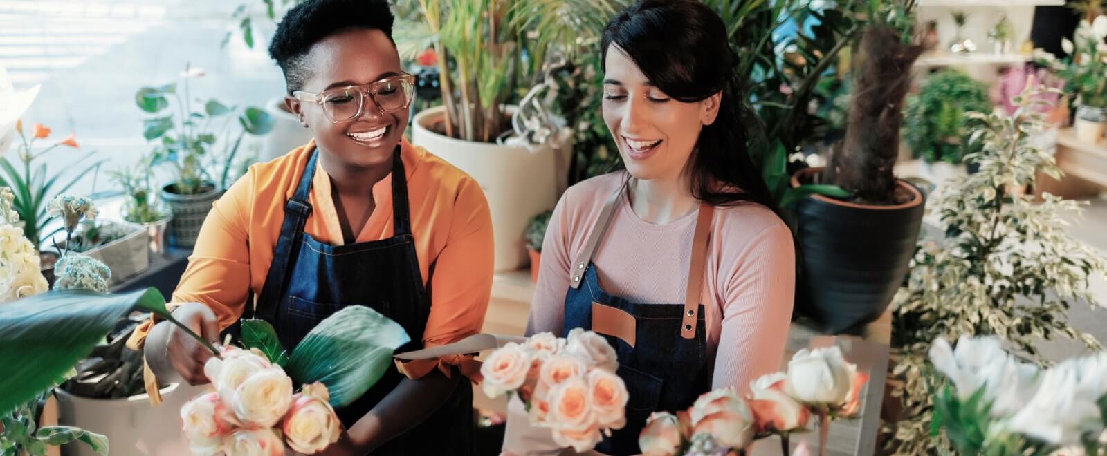 two workers in aprons arranging flowers