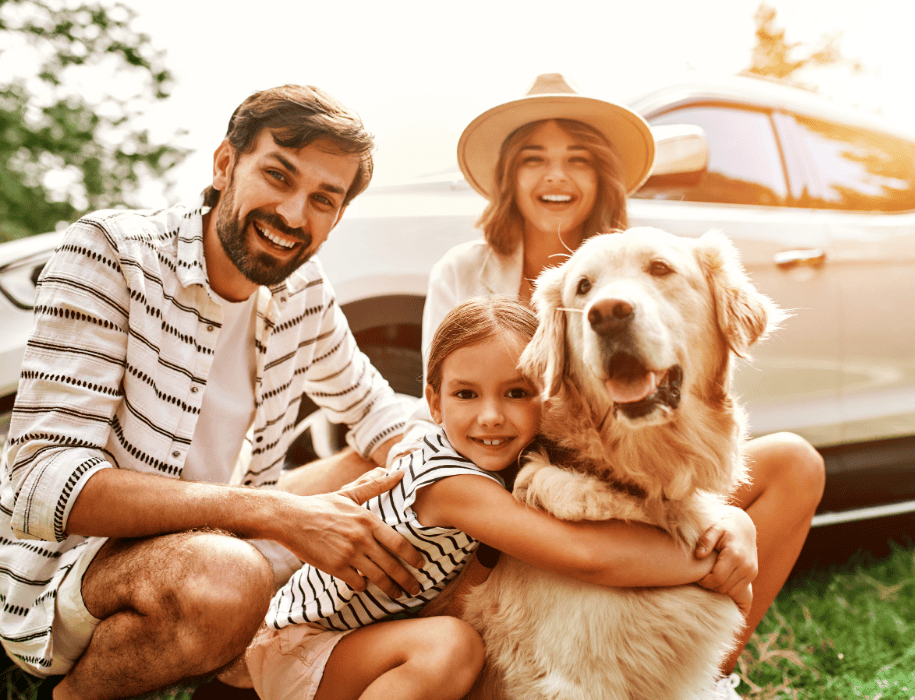 family and dog in front of car
