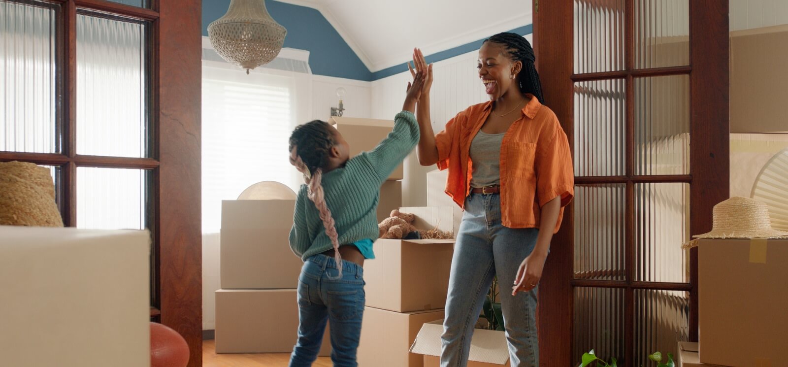 mom and young daughter high-fiving in a room with moving boxes